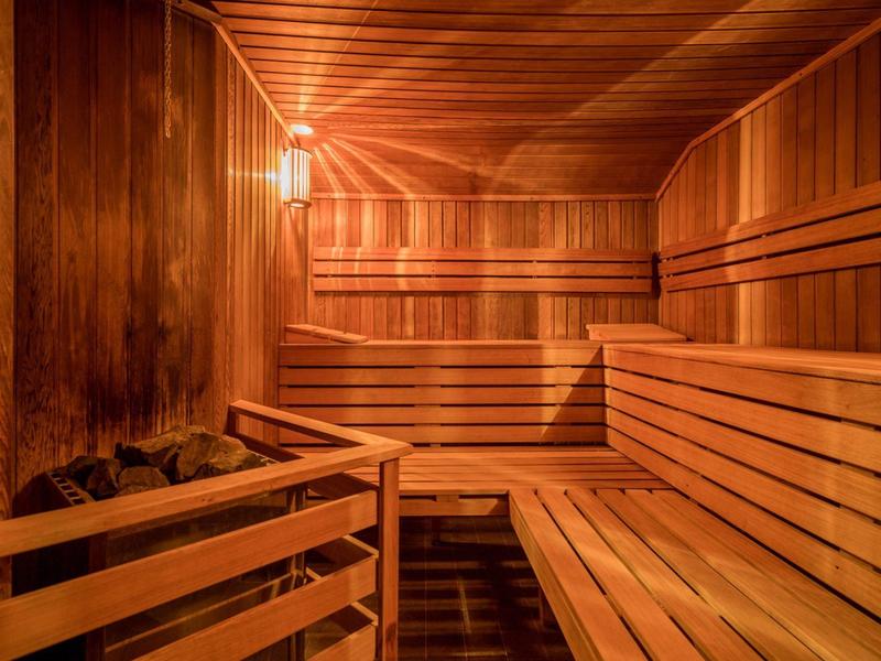 Interior de una sauna bien iluminada con paneles y bancos de madera.