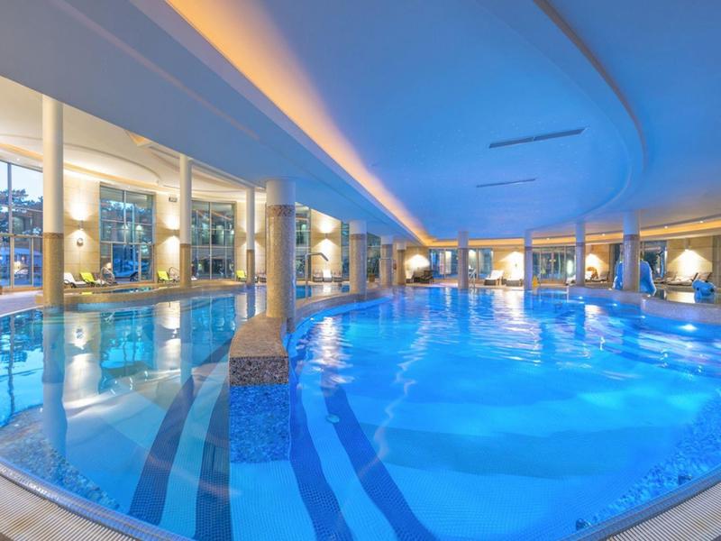 Piscina cubierta con agua iluminada en azul en un moderno spa de hotel