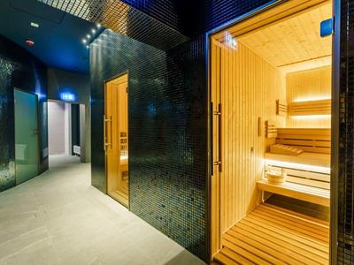 Moderne Sauna mit hellem Holz und angrenzendem dunklem Korridor im Wellnessbereich.