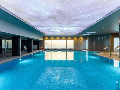 Innenpool mit beleuchteter Decke, umgeben von Holz und Glas im modernen Design.