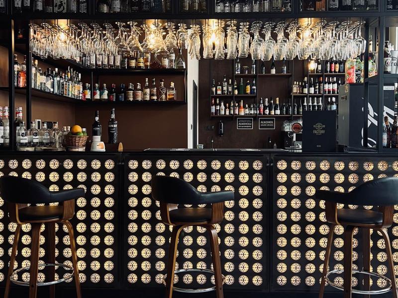 Moderne Bar mit drei Hockern und Wand aus runden Mustern im stilvollen Ambiente.