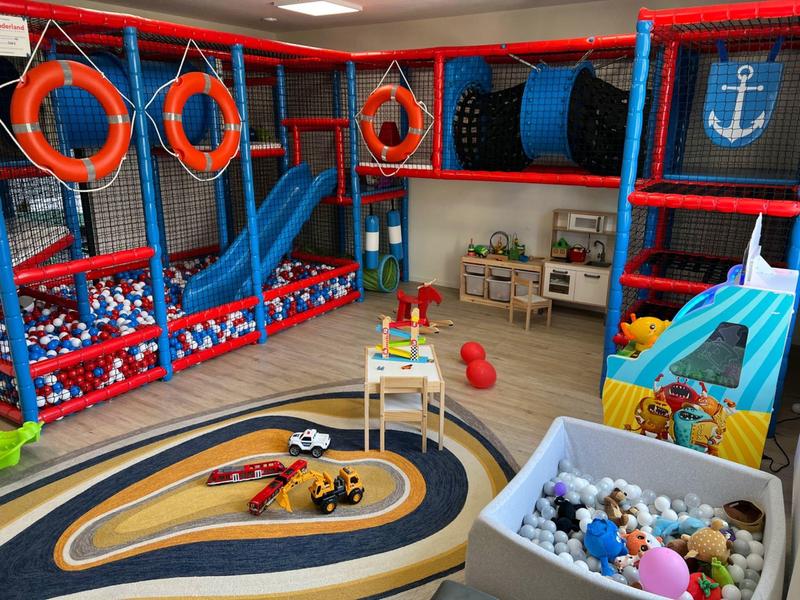 Bunter Kinderspielbereich mit Bällebädern, Rutschen und Spielzeug in einem Innenraum.