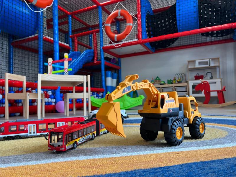 Bunter Indoor-Kinderspielplatz mit Spielsachen, Klettergerüst und Teppichboden.