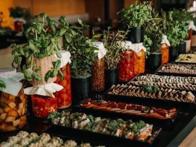 Bufet z marynowanymi warzywami i różnymi przystawkami w słoikach i na talerzach.