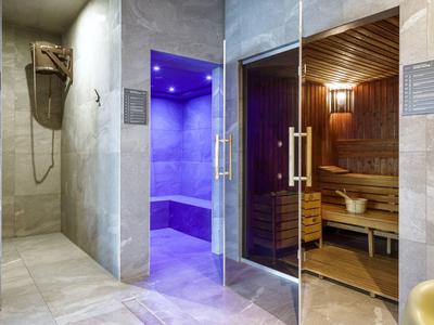 Widok na nowoczesną strefę spa z łaźnią parową i drewnianą sauną.