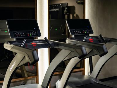 Trzy nowoczesne bieżnie z cyfrowymi wyświetlaczami w stylowej siłowni.
