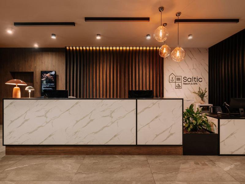 Nowoczesna recepcja hotelowa z marmurowym kontuarem i ciepłymi akcentami drewna oraz oświetlenia