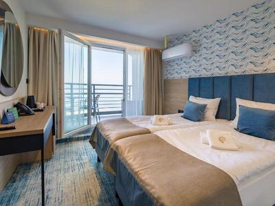 Habitación de hotel moderna con cama doble, escritorio y balcón con vista al mar.