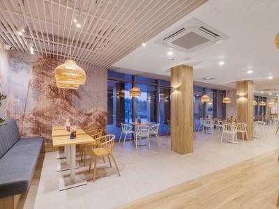 Moderní hotelová jídelna s dřevěným nábytkem a teplým osvětlením.