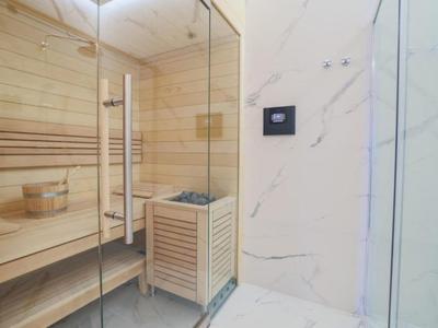 Moderní sauna s dřevěnými lavicemi a skleněnou stěnou v hotelovém pokoji.