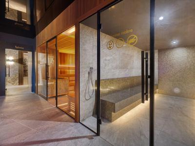 Moderní wellness prostor se saunou a relaxační místností, skleněné stěny a teplé osvětlení