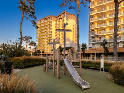 Dětské hřiště se skluzavkou před moderními osvětlenými bytovými domy za soumraku