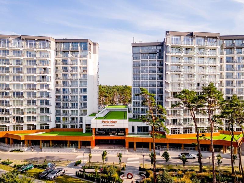 Moderní bytový komplex se dvěma vysokými budovami a zelenou venkovní plochou za jasné oblohy