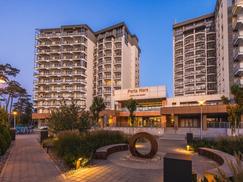 Hotelová budova s více patry a osvětleným vchodem za soumraku