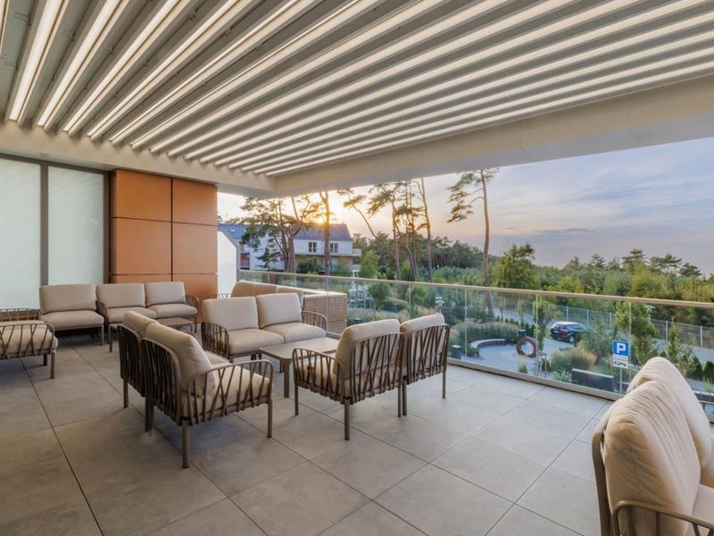 Prostorná terasa s posezením s výhledem na zahradu a západ slunce.