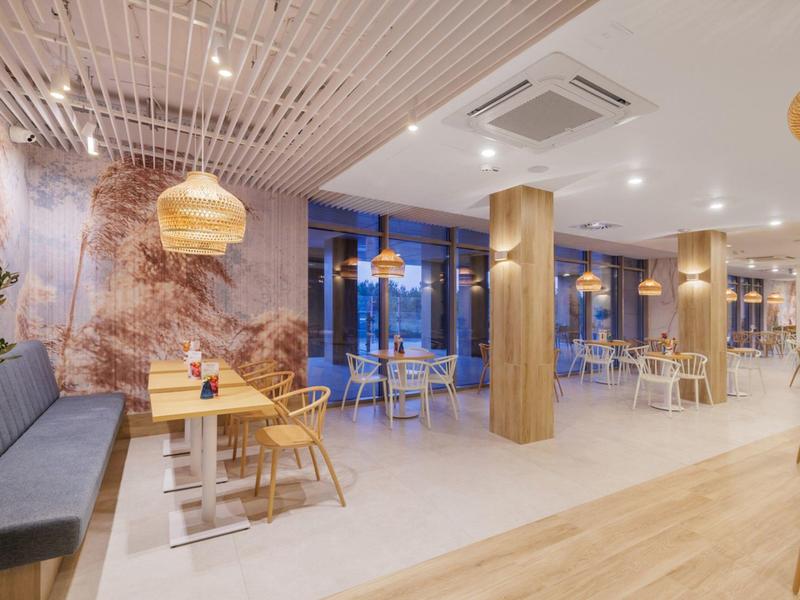 Moderní hotelová jídelna s dřevěným nábytkem a teplým osvětlením.