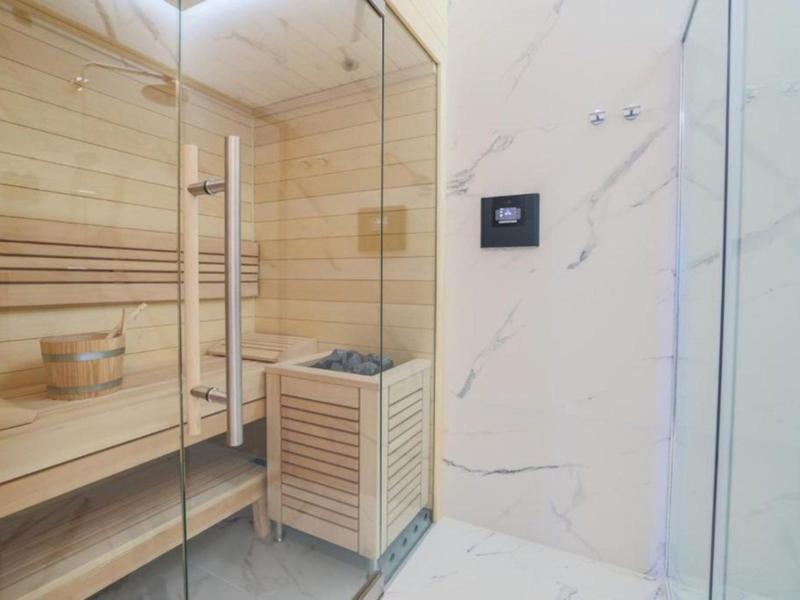 Moderní sauna s dřevěnými lavicemi a skleněnou stěnou v hotelovém pokoji.