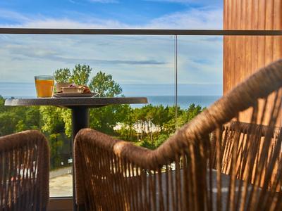 Balkon mit Blick auf das Meer, Korbsessel und ein Tisch mit Getränken und Snacks.