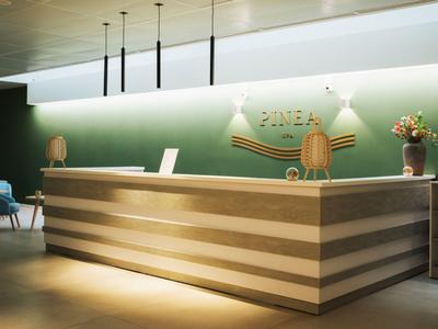 Modernes Hotellobby mit Holzrezeption, grünem Wanddekor und gemütlichen Sitzgelegenheiten.