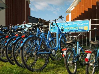Reihe blauer Fahrräder steht draußen vor einem Gebäude auf Grasfläche.