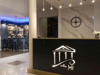 Eleganter Hotel-Empfangsbereich mit beleuchtetem Tresen und Bar im Hintergrund.