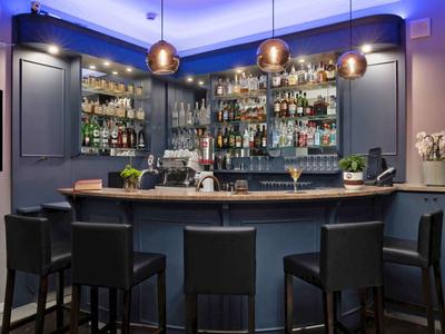 Elegante Hotelbar mit modernen Ledersesseln, beleuchteten Regalen und blauer Akzentbeleuchtung.