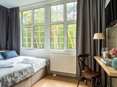 Hotelzimmer mit großem Fenster, Doppelbett, Schreibtisch und Vorhängen.