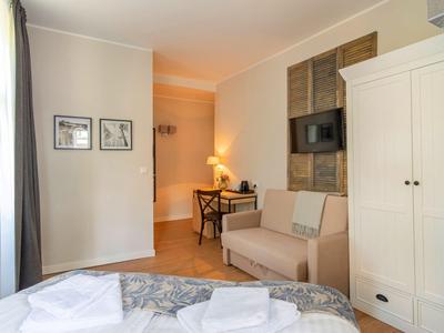 Helles Hotelzimmer mit Bett, Sofa, Schreibtisch, TV und Kleiderschrank.