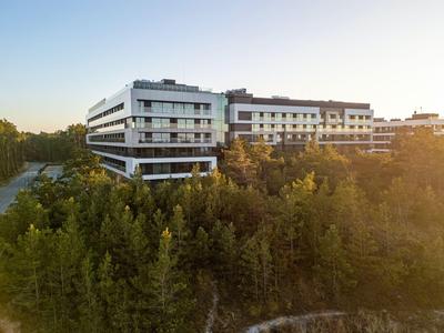 Edificio de hotel moderno rodeado de abundante vegetación y árboles al atardecer