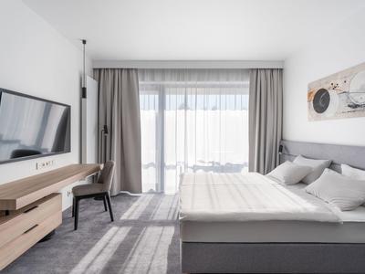 Habitación de hotel luminosa con cama doble, televisor de pantalla plana y gran ventana con cortinas.
