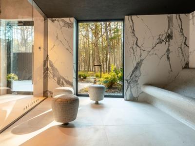 Área de spa moderna con detalles de mármol y gran pared de vidrio con vista al bosque