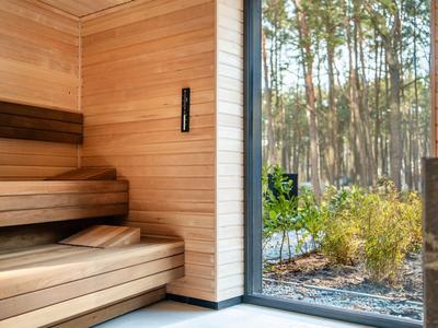 Sauna moderna con interior de madera y vista al área exterior arbolada.
