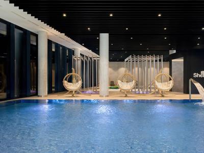 Piscina interior moderna con zona lounge y cómodas sillas colgantes en hotel