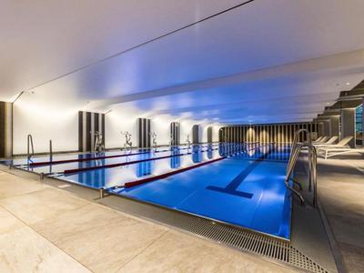 Vnitřní bazén s modrým osvětlením a lehátky u vody.