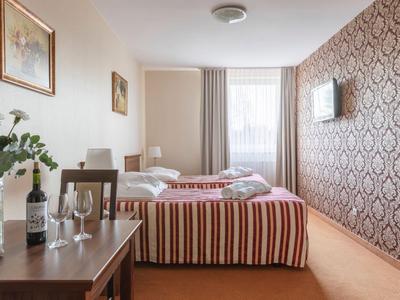 Camera d'hotel moderna con due letti singoli, tavolo, sedie e grande finestra.