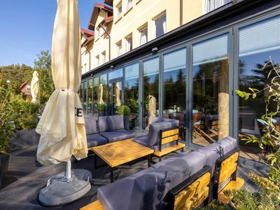 Accogliente terrazza esterna dell'hotel con posti a sedere e ombrellone alla luce del giorno.
