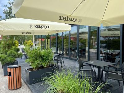 Terrazza di un hotel con tavoli, sedie e ombrelloni in una giornata nuvolosa.