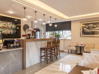 Bar dell'hotel moderna con sedie di legno, pavimento in marmo e piastrelle, illuminazione luminosa e un bar con bevande.