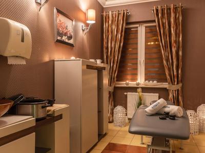 Accogliente stanza per trattamenti con lettino massaggi, colori caldi e illuminazione soffusa.