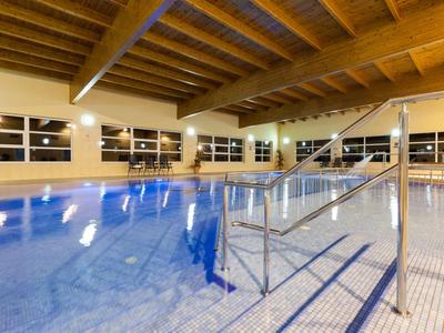 Piscina coperta luminosa con soffitto in legno e grandi finestre per nuotare rilassati.