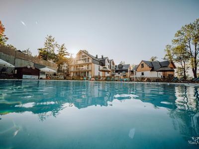 Piscina coperta con vista su hotel moderni e alberi sotto un cielo sereno.