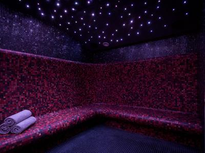 Locale riscaldato con mosaico rosso e soffitto illuminato a stelle, due asciugamani posati.