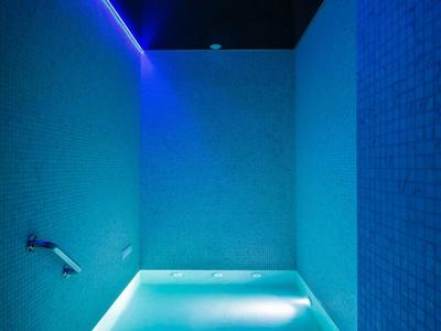Area benessere moderna con piscina illuminata e asciugamani arrotolati.