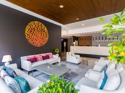 Lobby dell'hotel moderna con divani eleganti, decorazioni e piante in uno spazio luminoso.
