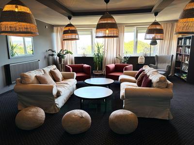 Lounge moderna dell'hotel con divani comodi, tavoli rotondi e lampade a sospensione calde.