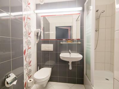 Bagno compatto con WC, lavabo, specchio e cabina doccia in colori neutri.