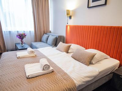 Camera d'hotel moderna con letto matrimoniale, testiera arancione e biancheria beige.