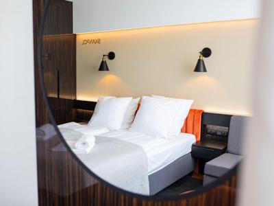Camera d'hotel moderna con letto matrimoniale, lampade da comodino e biancheria bianca.