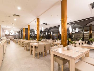 Ristorante moderno con legno chiaro, sedie bianche e grandi finestre per ospiti in vacanza.