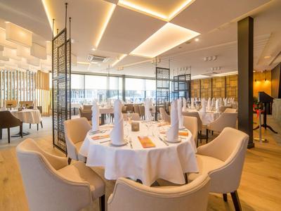 Ristorante elegante in hotel con design moderno, tavoli rotondi apparecchiati e sedie confortevoli.